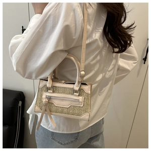 Detalle de textura trenzada en un bolso bandolera beige con asa de cuero elegante