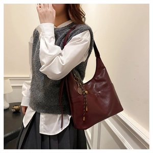 Détail d'un sac Hobo bordeaux avec poches latérales et accessoire pendentif de tennis