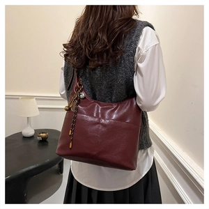 Détail du sac fourre-tout bordeaux avec breloque tissée et pendentif rond en métal