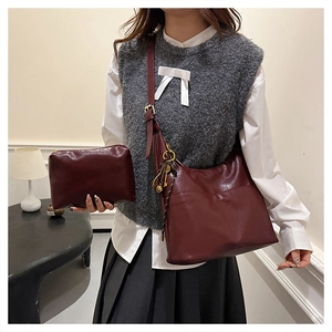 Détail du sac fourre-tout bordeaux et de la pochette assortie avec charm doré élégant