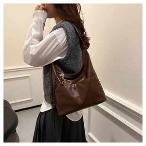 Detail of brown vintage hobo tote bag featuring front dual pockets and tennis racket charm