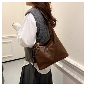 Vue latérale d'un sac cabas en cuir ciré marron foncé avec pendentif tissé élégant