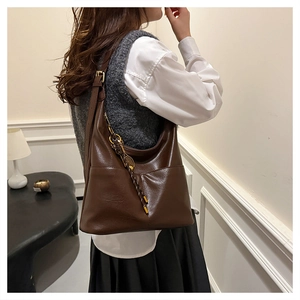 Détail du sac fourre-tout marron foncé avec boucle dorée et charm raquette de badminton