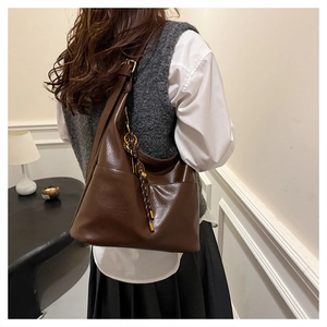 Detail of a large brown leather tote bag showing wide strap and quality stitching