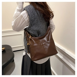 Détail du sac cabas en cuir marron foncé avec un pendentif créatif en forme de raquette