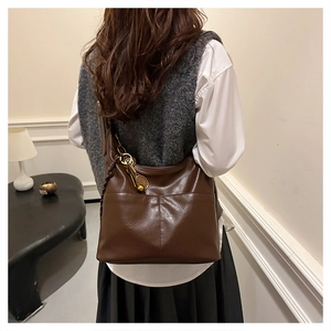Détail d'un sac cabas en similicuir marron foncé avec un pendentif raquette sur le côté
