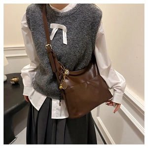 Detail of vintage brown leather tote bag featuring a tennis racket charm and tassels