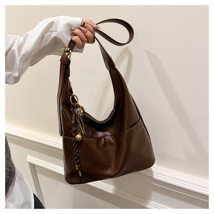 Close-up of retro brown hobo bag with tassel detail and textured glossy leather finish
