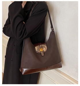 Détail d'un sac Hobo marron avec textures mixtes et boucle dorée ronde avec le logo N gravé