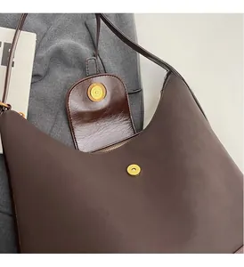 Détail d'un cabas en cuir marron foncé avec un fermoir magnétique rond doré