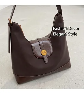 Détail du sac demi-lune en cuir marron foncé avec une boucle dorée en forme de N