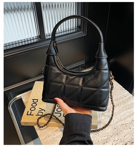 Détail de la texture matelassée et de la chaîne dorée sur ce sac chic en cuir noir