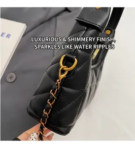 Détail de la quincaillerie dorée brillante et du cuir noir matelassé d'un sac à chaîne