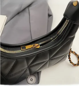 Détail de la fermeture dorée fluide et de la texture cuir matelassé noir du sac