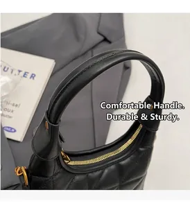 Détail d'un sac à main noir matelassé avec fermeture éclair dorée et anse solide