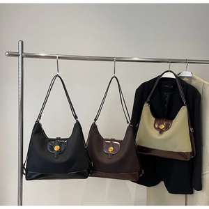 Trois sacs hobo en noir, café et beige suspendus sur des cintres en acier inoxydable