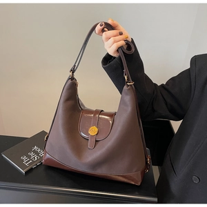 Détail du sac hobo marron vintage en toile et cuir avec logo métallique doré élégant