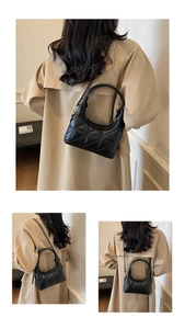 Détail du sac croissant en cuir matelassé noir avec bandoulière chaîne sur trench