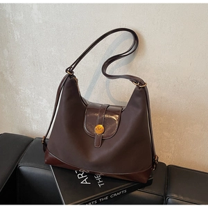 Détail d'un sac cabas marron foncé vintage avec logo doré et fermeture éclair sur livres