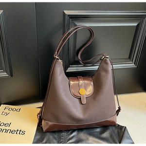Détail du sac à bandoulière marron foncé avec boucle dorée en N et textures mates