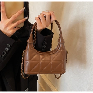 Détail d'un sac à main matelassé marron avec bandoulière chaîne et poignée incurvée