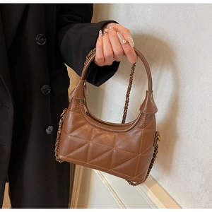 Détail du sac à main en cuir matelassé marron avec chaîne dorée et coutures texturées