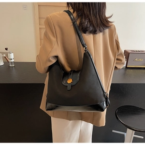 Détail d'un sac hobo noir en similicuir mat et verni avec boucle métallique ronde de style