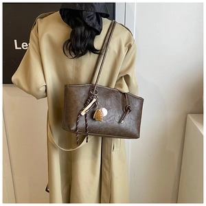 Brown leather tote bag with baseball charms shown on model for size and fit reference
