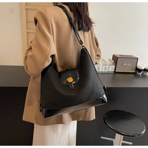 Détail du sac cabas noir avec boucle dorée et mélange de matières porté par un mannequin