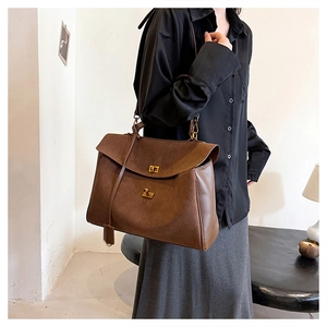 Detail of dark brown faux suede tote bag featuring a gold twist-lock and top handle