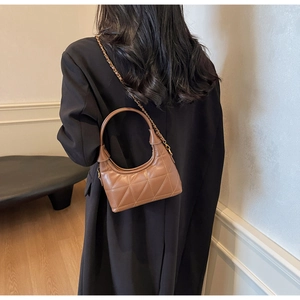 Sac demi-lune en cuir matelassé marron avec chaîne dorée sur mannequin en blazer noir