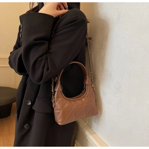 Détail du sac matelassé marron avec coutures géométriques et bandoulière en chaîne dorée