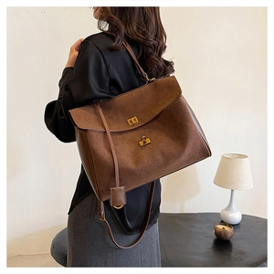 Detailed view of brown suede tote bag featuring a vintage gold twist lock and a flap closure
