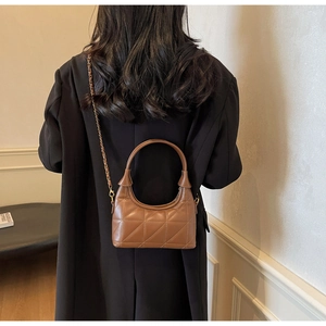Sac à bandoulière en cuir matelassé marron porté sur une veste de blazer noire