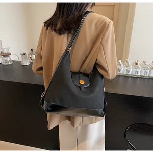 Détail du sac hobo noir avec textures mates et brillantes et boutons pression dorés