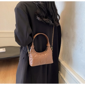 Détail de la texture matelassée marron et chaîne dorée sur le sac demi-lune