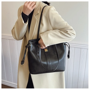 Detail of black tote bag featuring gold square hardware and adjustable side drawstrings