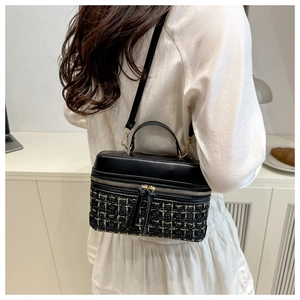 Détail du sac boîte en tweed avec doubles fermetures éclair dorées et poignée en cuir