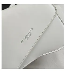 Detailed close-up of white lychee texture leather with silver FASHION TREND engraving