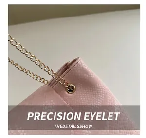 Detail of pink snakeskin texture handbag with gold grommets and a sleek metal chain strap
