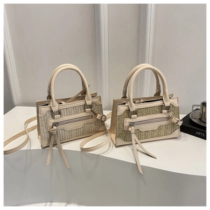 Detalle de bolso de paja tejida con adornos de cuero y borla larga en la cremallera