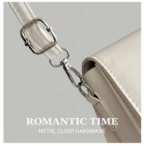 Detail view of cream leather shoulder bag featuring silver metal hook and adjustable strap