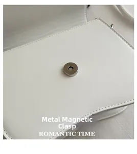 Detail of the silver magnetic closure on a white minimalist leather shoulder bag