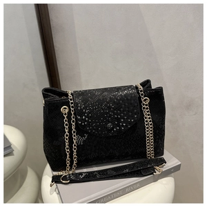 Détail de la texture serpent noire sur le sac à bandoulière avec chaînes dorées chic