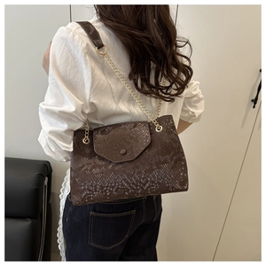 Détail d'un sac à bandoulière marron foncé à motif serpent avec une chaîne dorée élégante