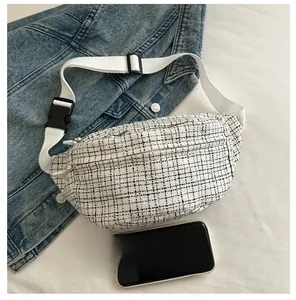 Vue détaillée du sac banane en tweed à carreaux avec zips et smartphone pour échelle
