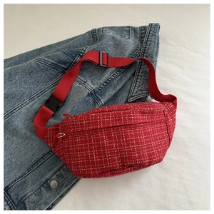 Détail du sac de poitrine en tweed rouge avec motif à carreaux dorés et sangle en toile