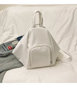 Detail view of white geometric backpack showing matte synthetic leather and front zipper pocket