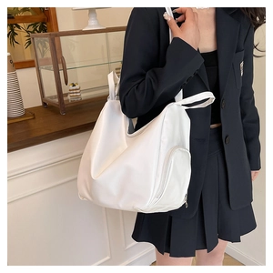Detail of white tote bag showing the side zipper pocket and smooth synthetic leather texture