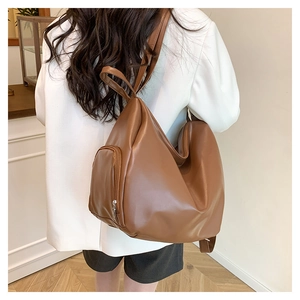 Brown leather tote bag side view on model showing spacious design and zipper detail